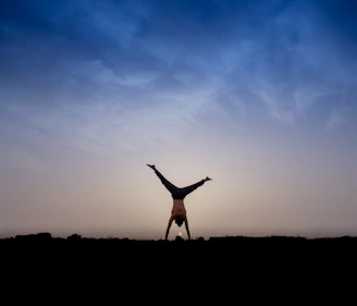 A powerful handstand held confidently against a vibrant sunset sky.