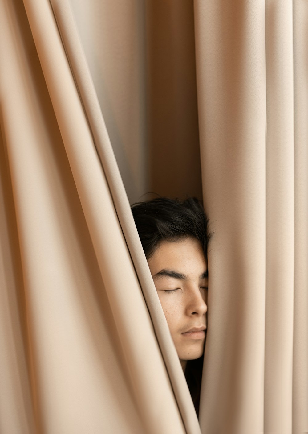 man leaning on brown curtain