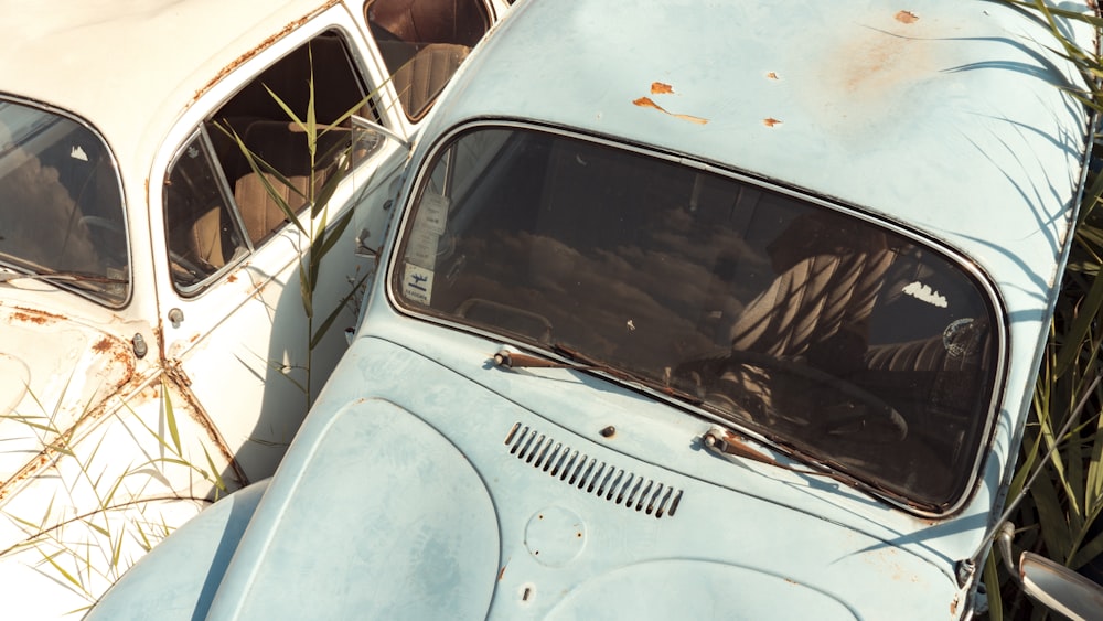 teal classic car parked beside white metal fence during daytime