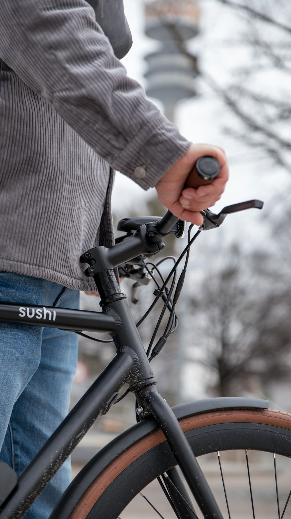 person in brown coat and blue denim jeans riding black bicycle