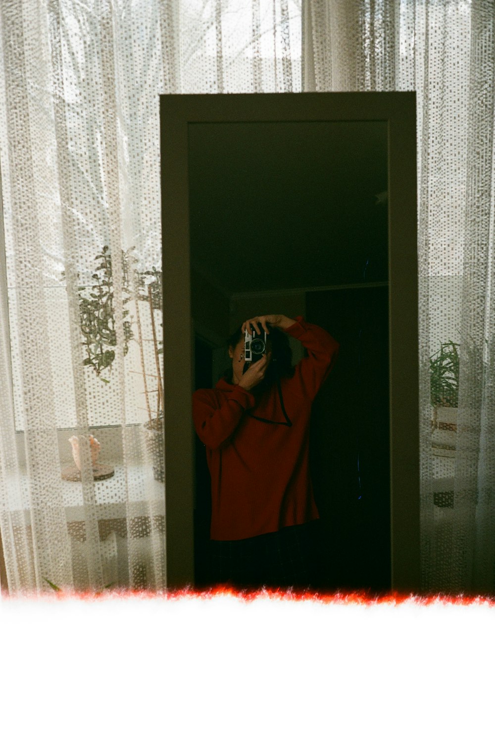 woman in red robe standing near white floral curtain