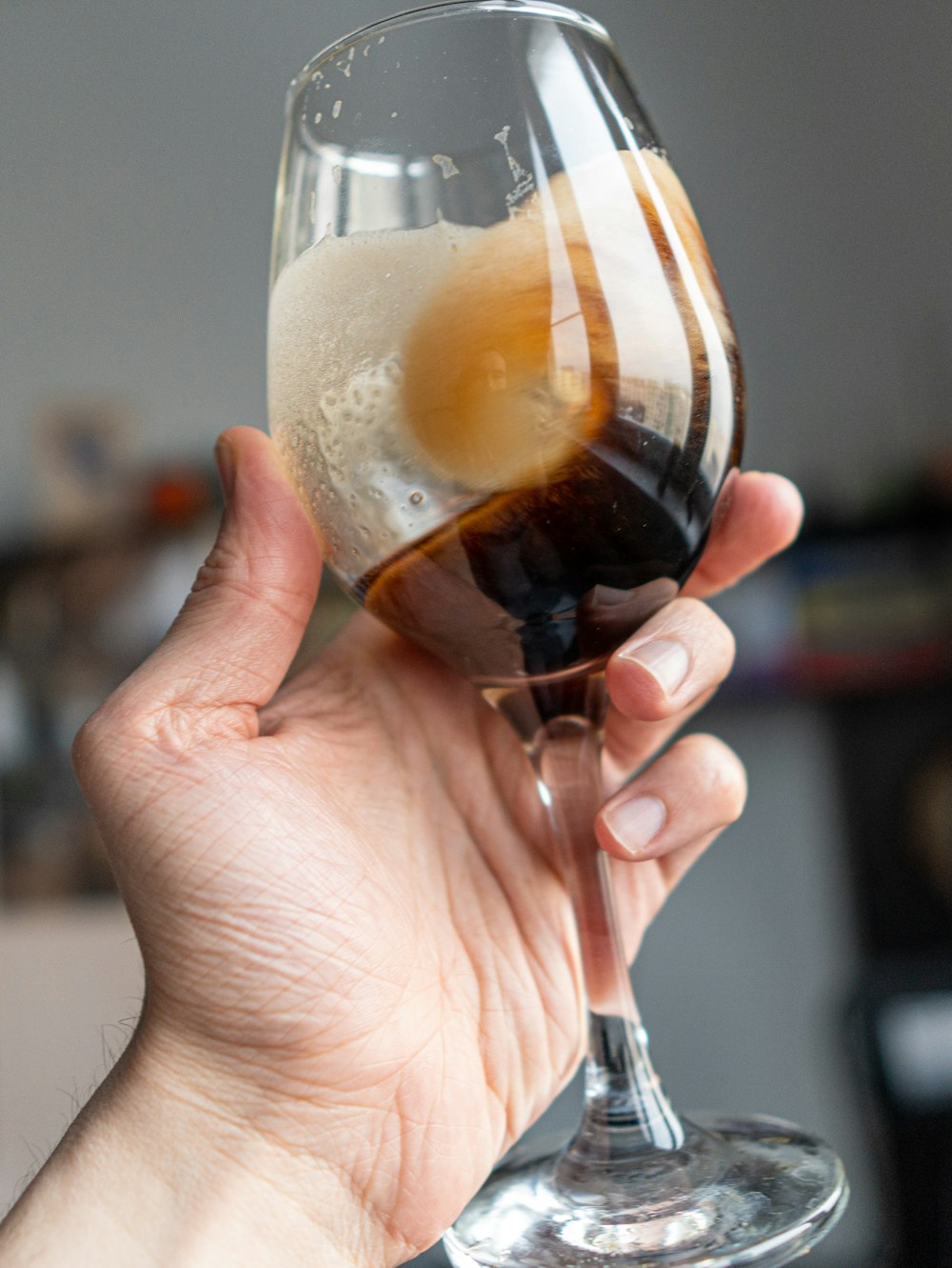 person holding clear glass bottle with brown liquid