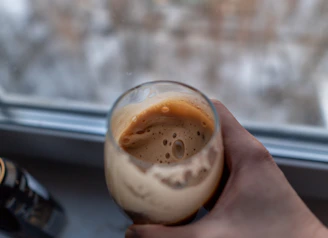 Top view of a hand holding a cold brew coffee with condensation droplets on the glass