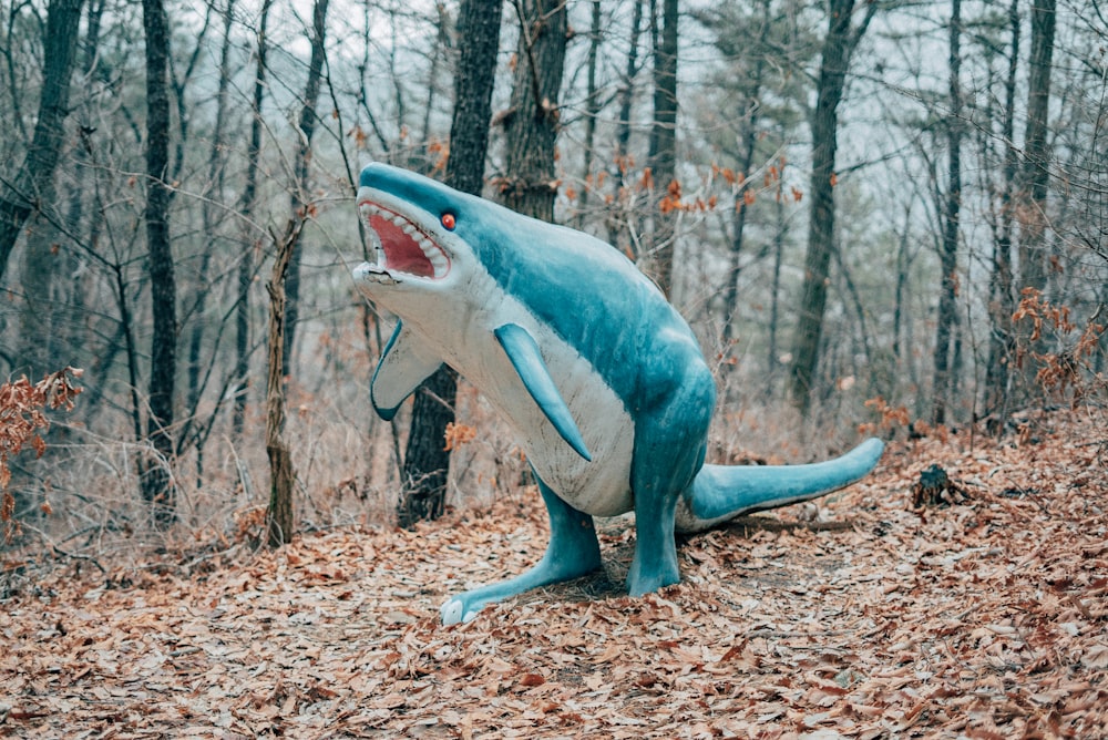 Figurina di squalo blu e bianco su foglie secche marroni