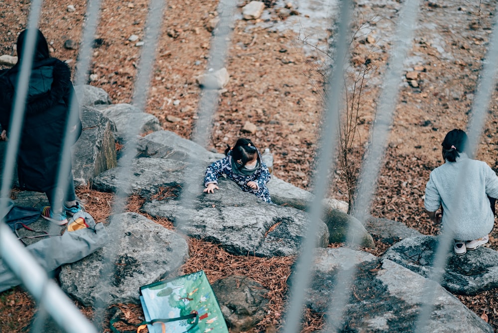 woman in black and white long sleeve shirt sitting on gray rock during daytime