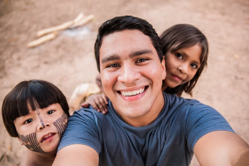 A smiling solo traveler taking a photo with new friends in a bustling market.