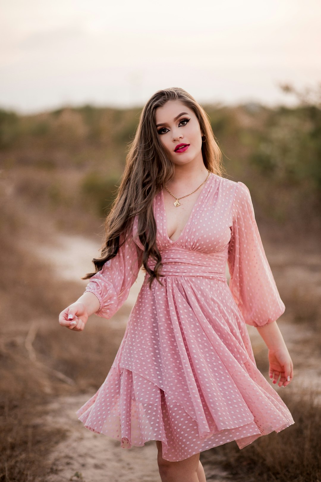 girl in pink dress standing on brown field during daytime