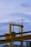 A large, industrial structure with yellow beams and railings stands under a mostly cloudy sky. A streetlight with a solar panel is fixed to the right side of the structure. There are various cables and machinery components visible around the structure.