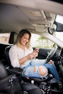 woman in white shirt and blue denim jeans sitting on car seat