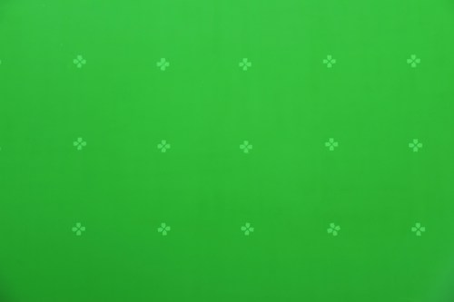 A bright green background features a pattern of small, evenly spaced white cross-like markers.