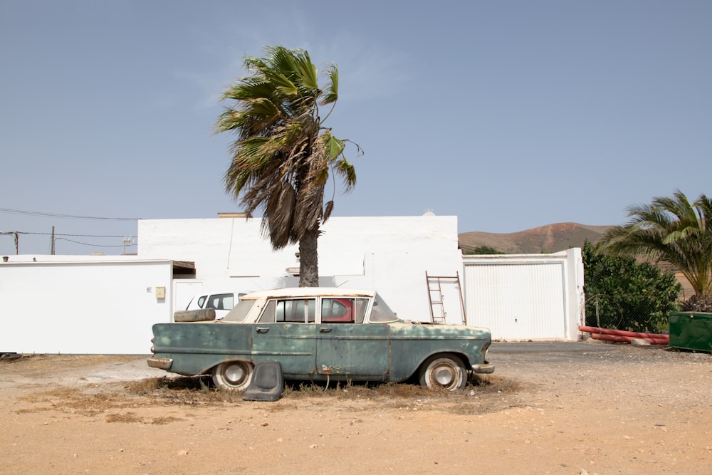 green and white vintage car parked beside white concrete building during daytime