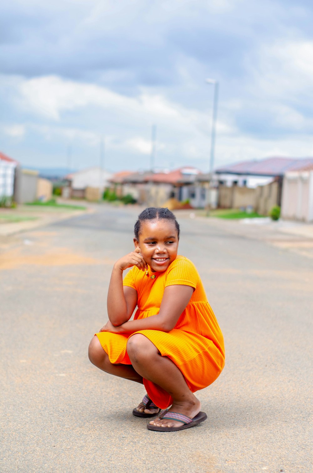 boy in yellow t-shirt and orange shorts sitting on gray concrete floor during daytime