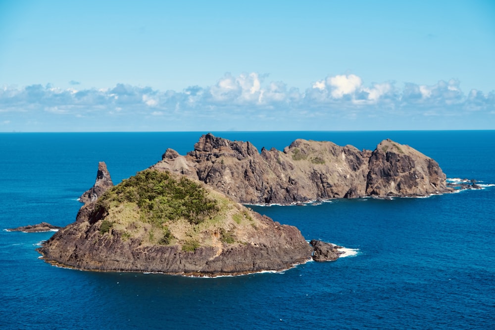 green and brown rock formation on blue sea under blue sky during daytime