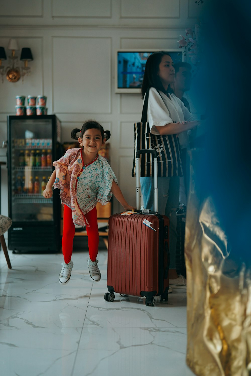 a little girl is jumping in the air with a suitcase
