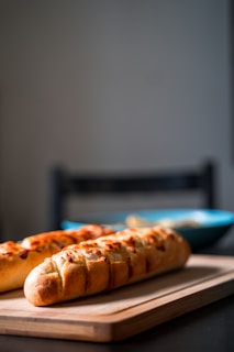 Freshly baked baguettes stacked with a hint of blue cloth in the background.