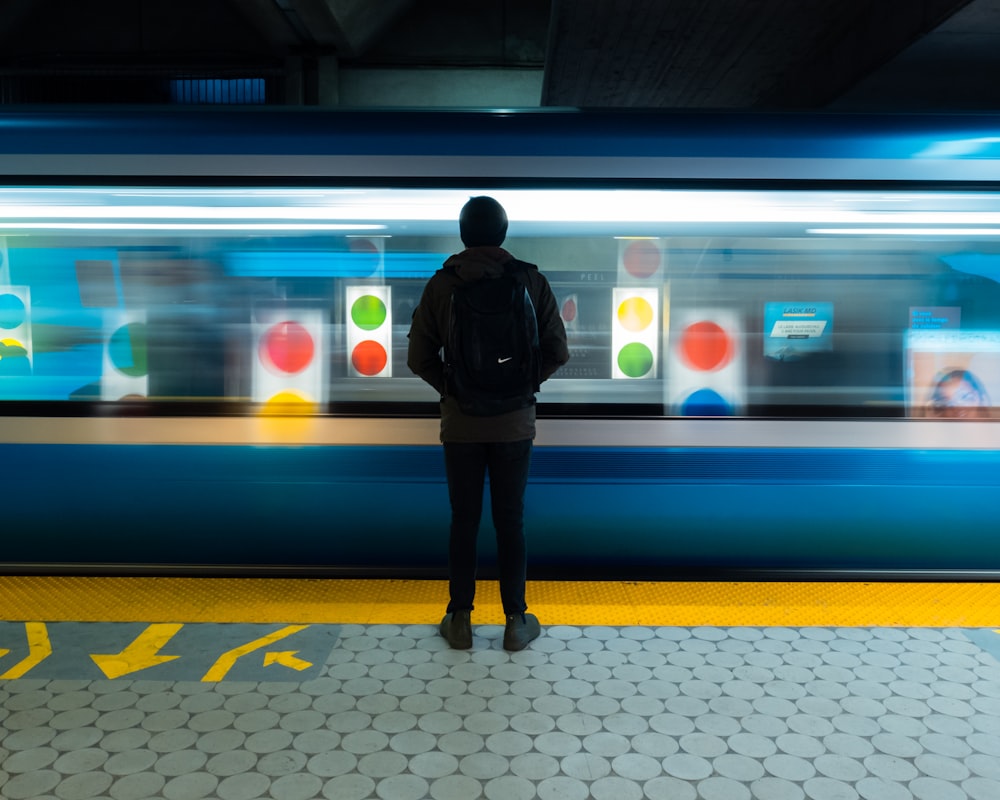 man in black jacket standing on train station