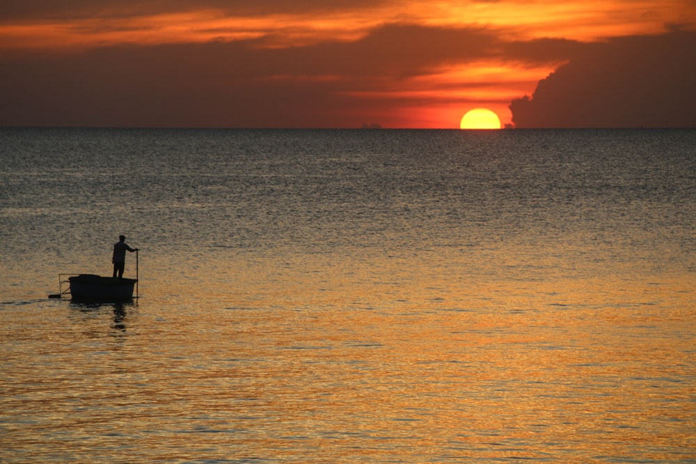 silhouette of boat on sea during sunset