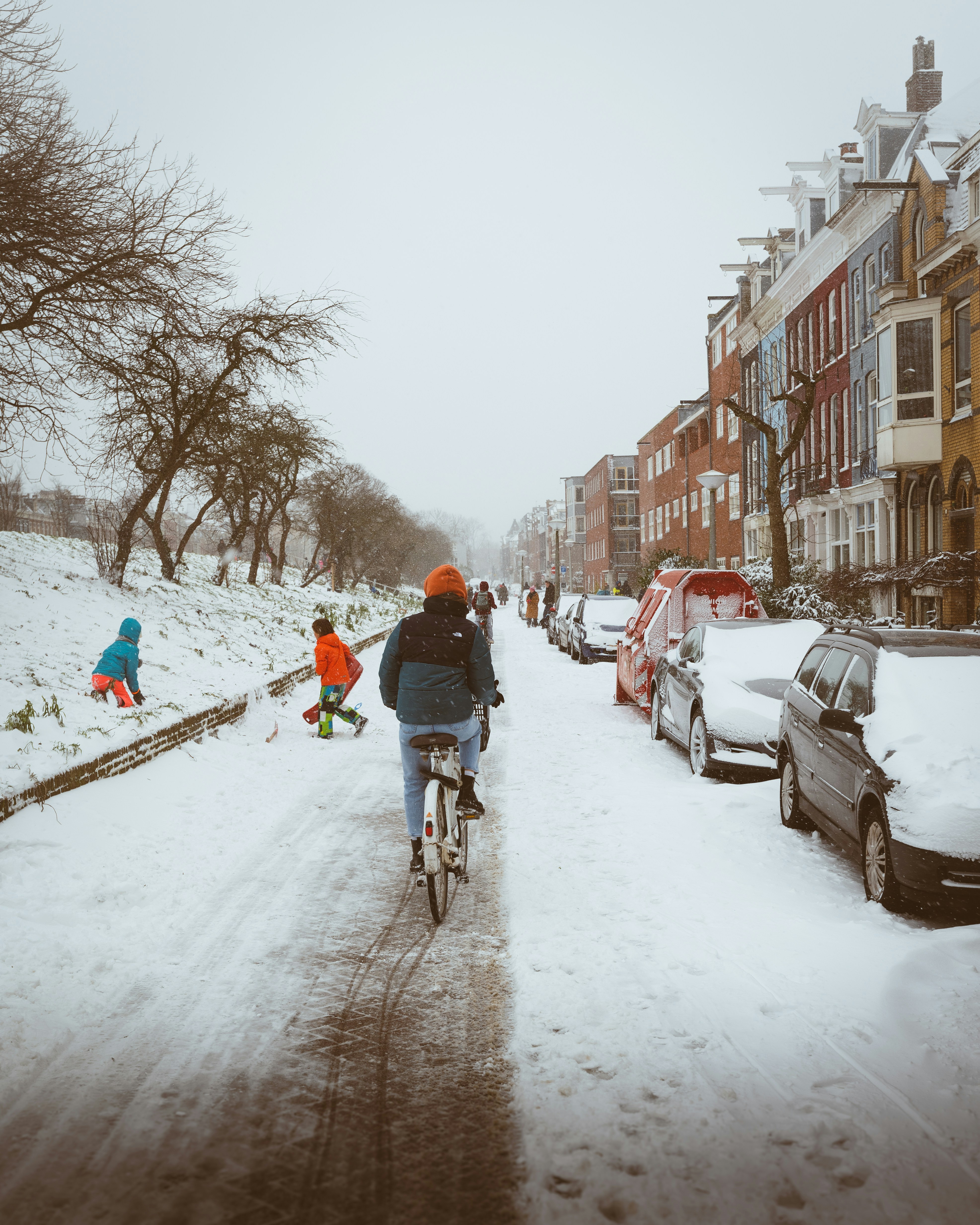 man in red jacket riding bicycle on snow covered road during daytime