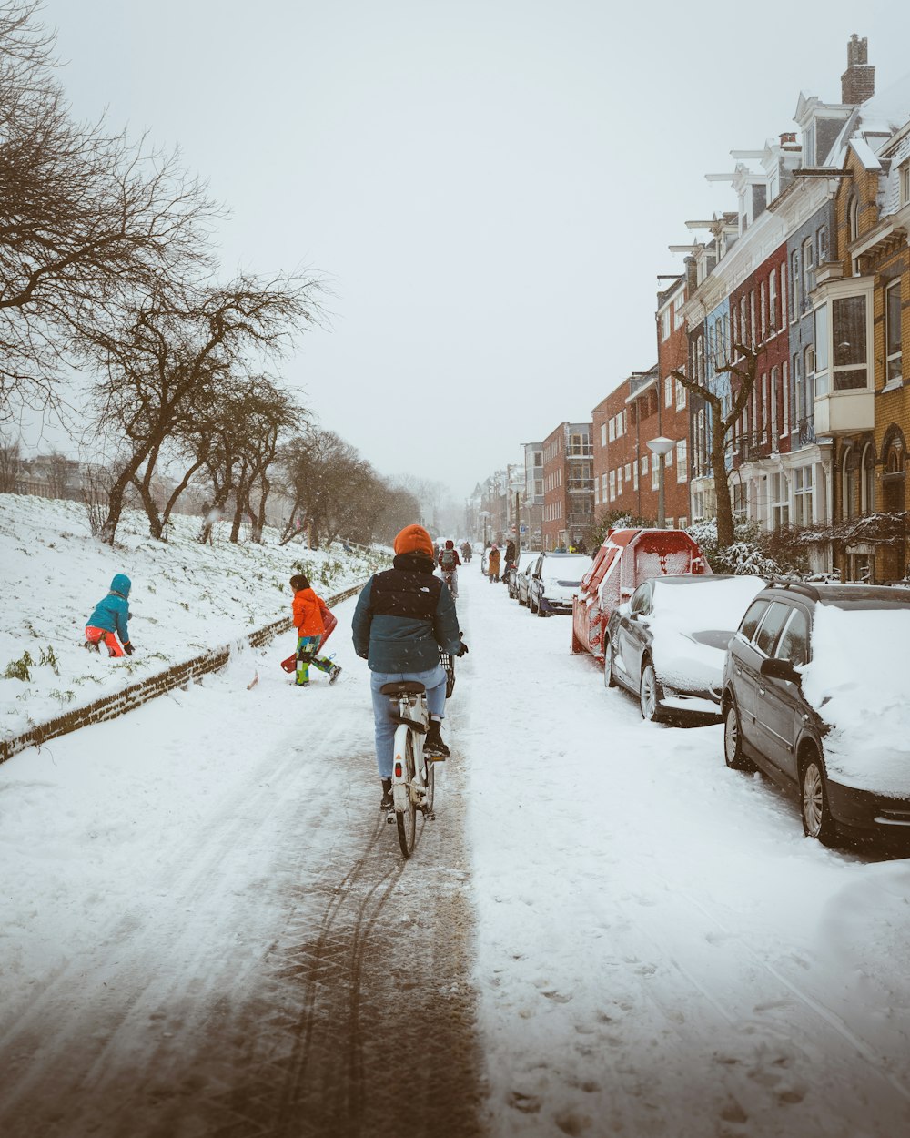 man in red jacket riding bicycle on snow covered road during daytime