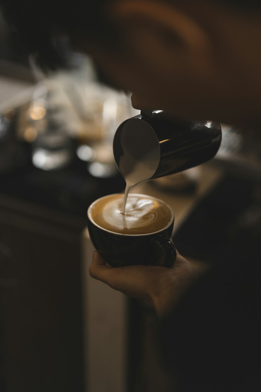 person pouring coffee on black ceramic mug