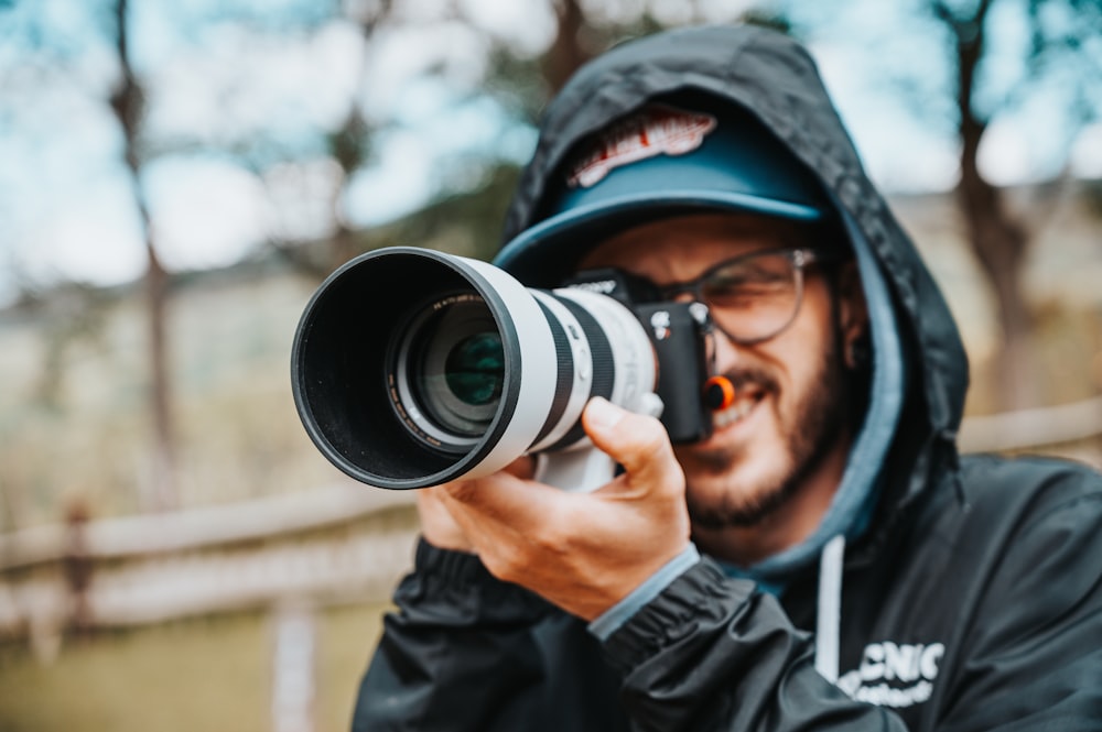 man in black jacket holding black dslr camera