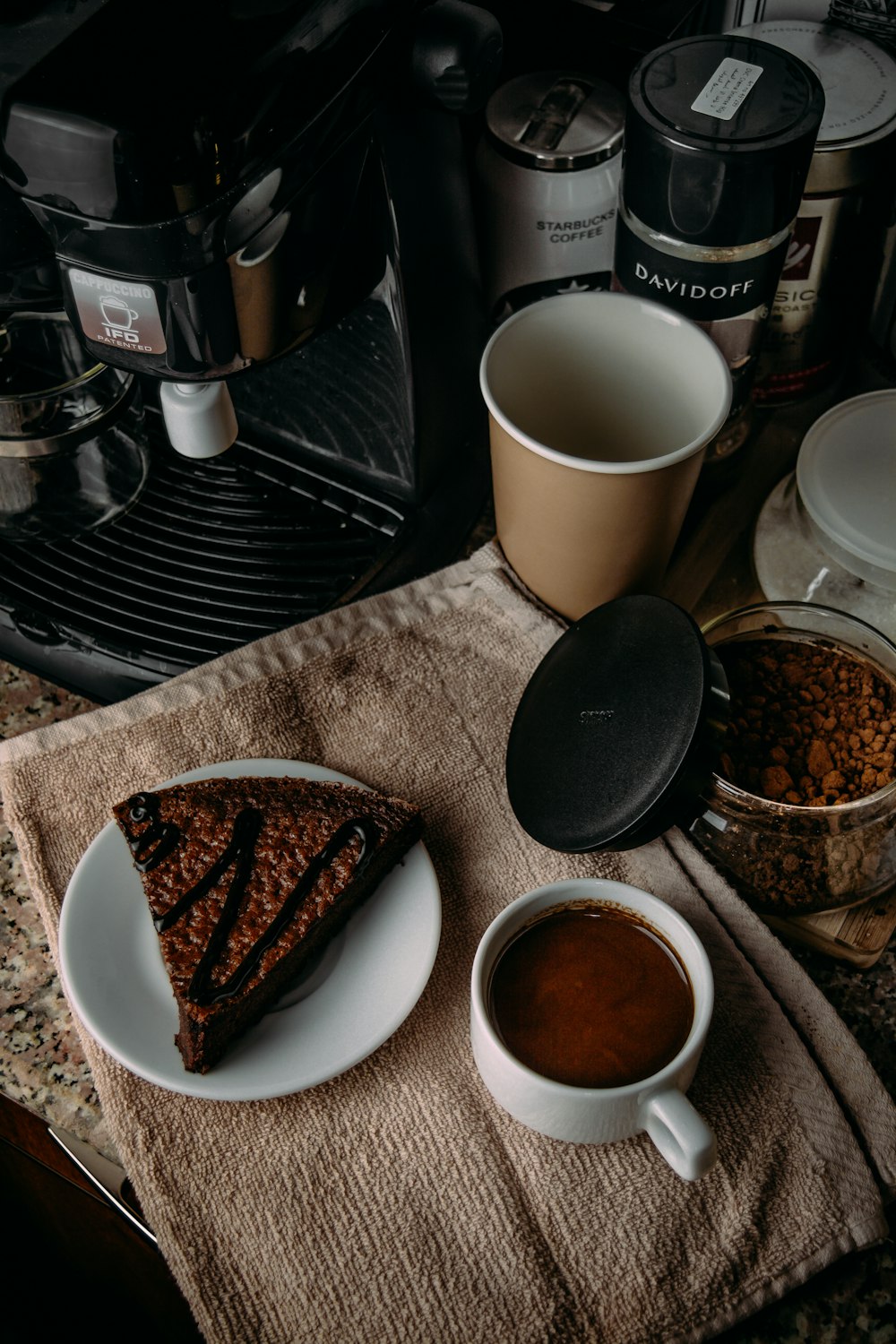 white ceramic mug beside black and silver coffee maker