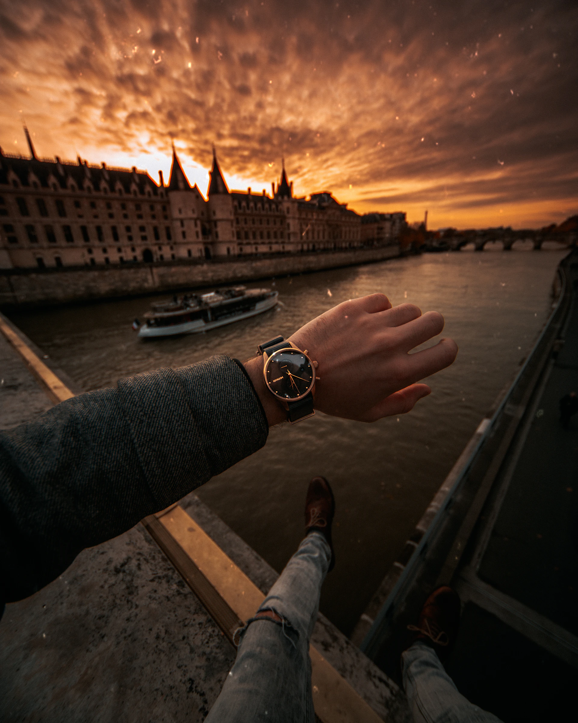 A stylish wrist wearing a Swiss luxury watch against a backdrop of a city skyline at sunset