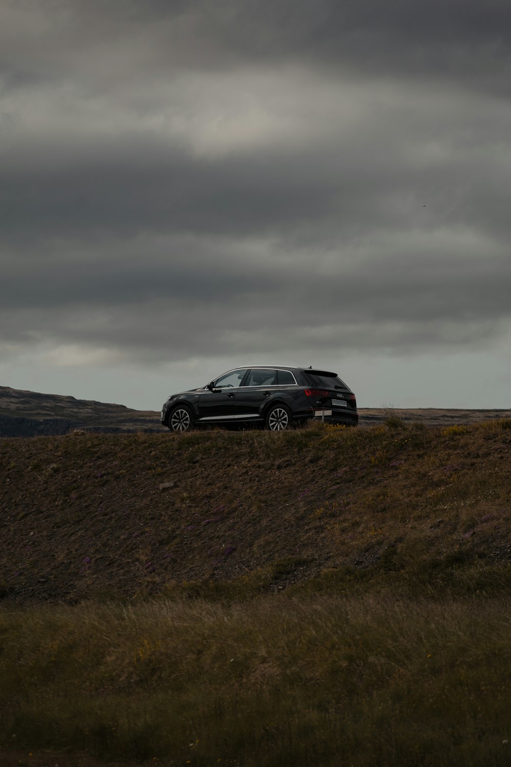 black suv on green grass field under gray cloudy sky