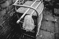 A professional-grade mop with a wooden handle resting against a clean, tiled floor.