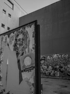 A stark black-and-white photograph capturing a raw street art mural in Johannesburg, textured with peeling paint and bold brushstrokes.