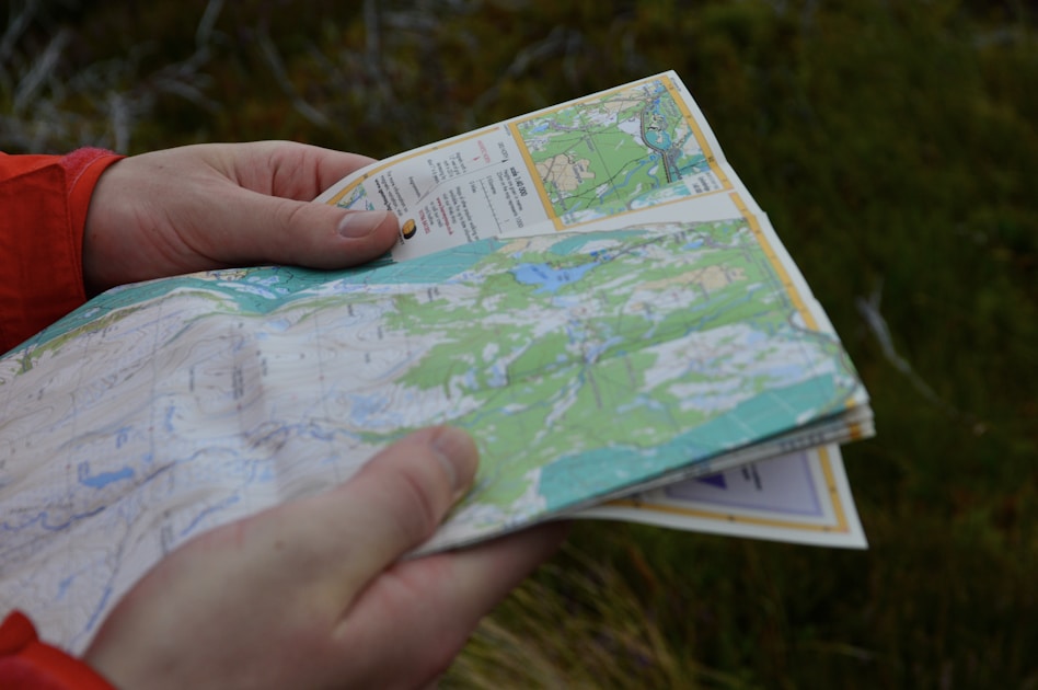 Hand holding a trail map outdoors with green landscape in the background — planning where to hunt