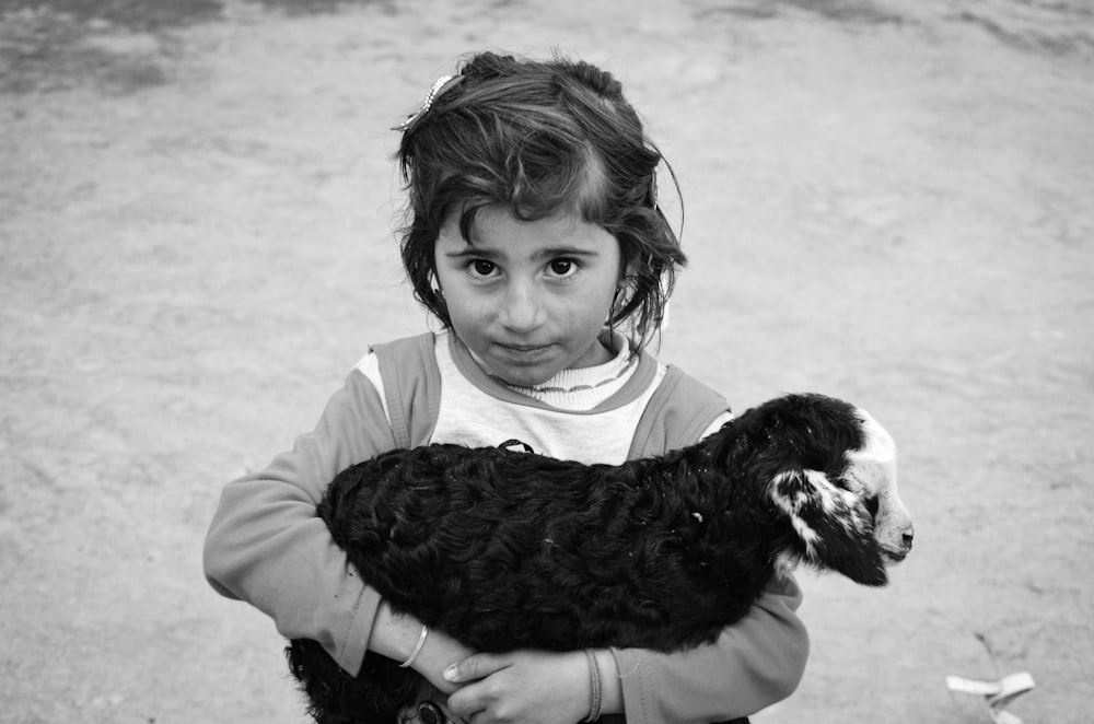 grayscale photo of girl hugging black short coated dog