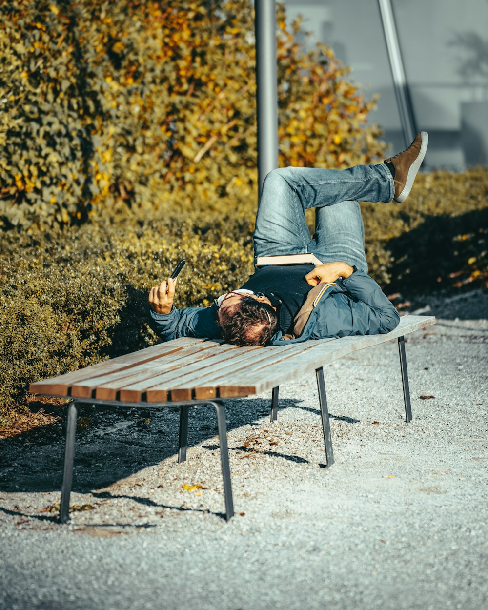 man in gray long sleeve shirt and black pants sitting on brown wooden bench