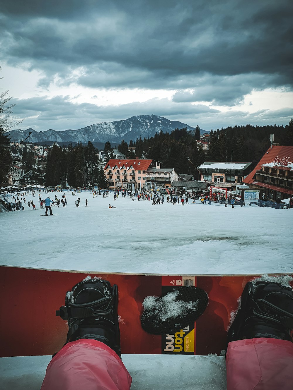 red and black snow covered houses near green trees and mountain during daytime