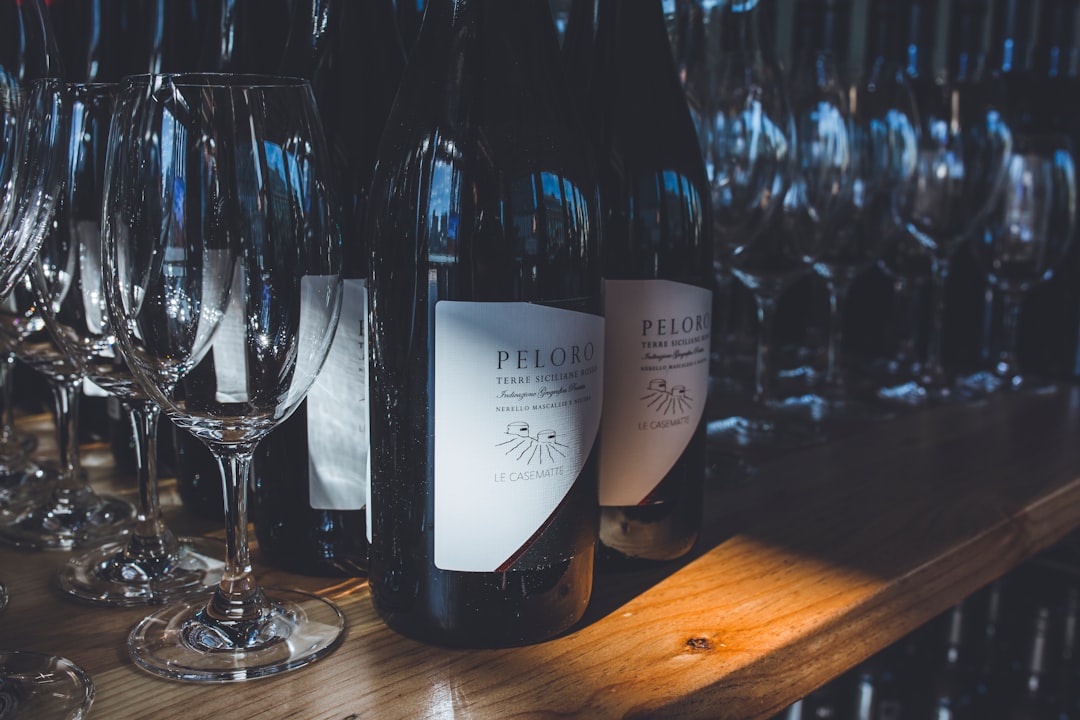 white labeled bottle beside clear wine glass