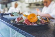 A chef’s hands artfully arranging fresh ingredients on a colorful antipasto platter.