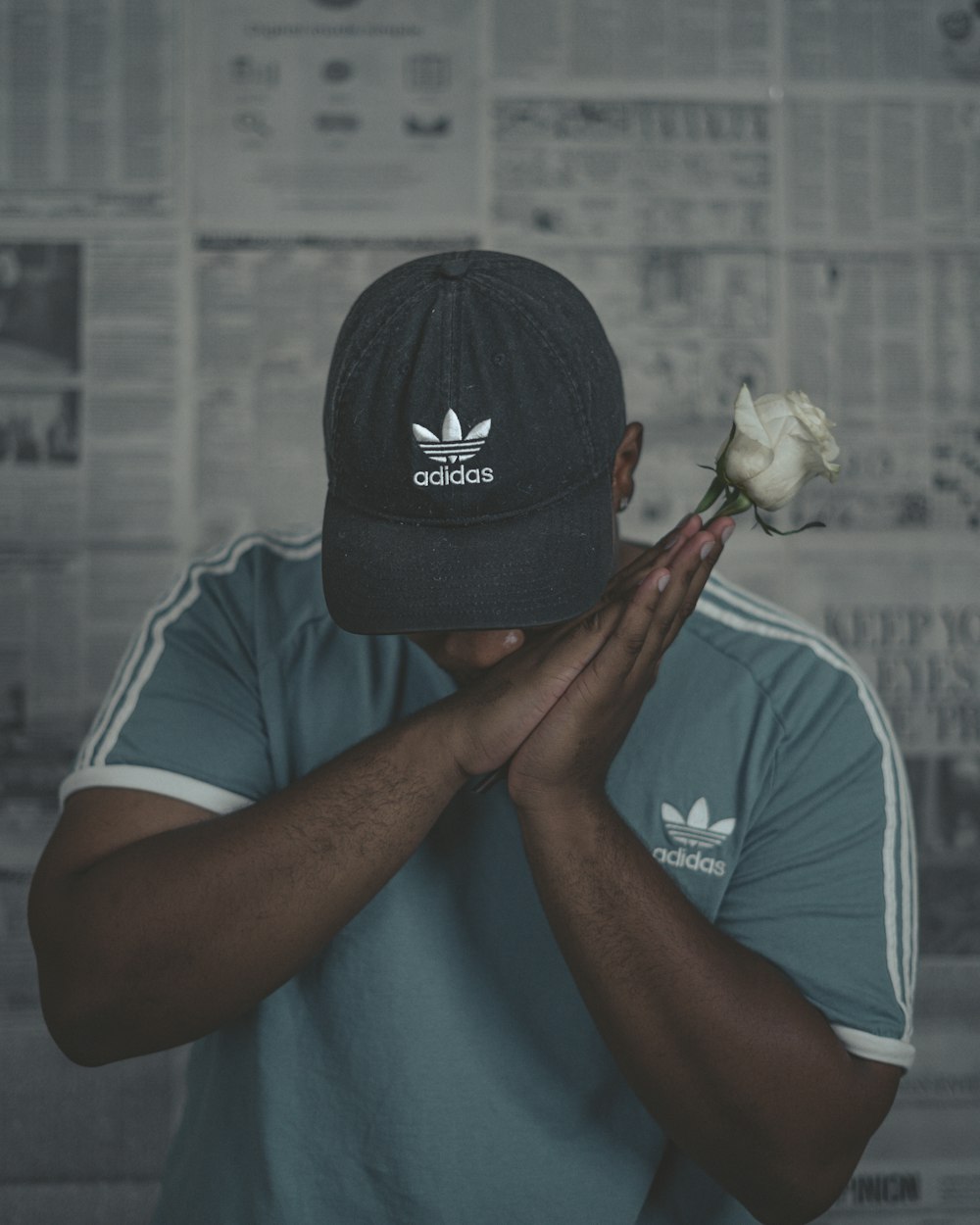 man in gray crew neck t-shirt wearing black cap holding white flower photo  – Free Grey Image on Unsplash
