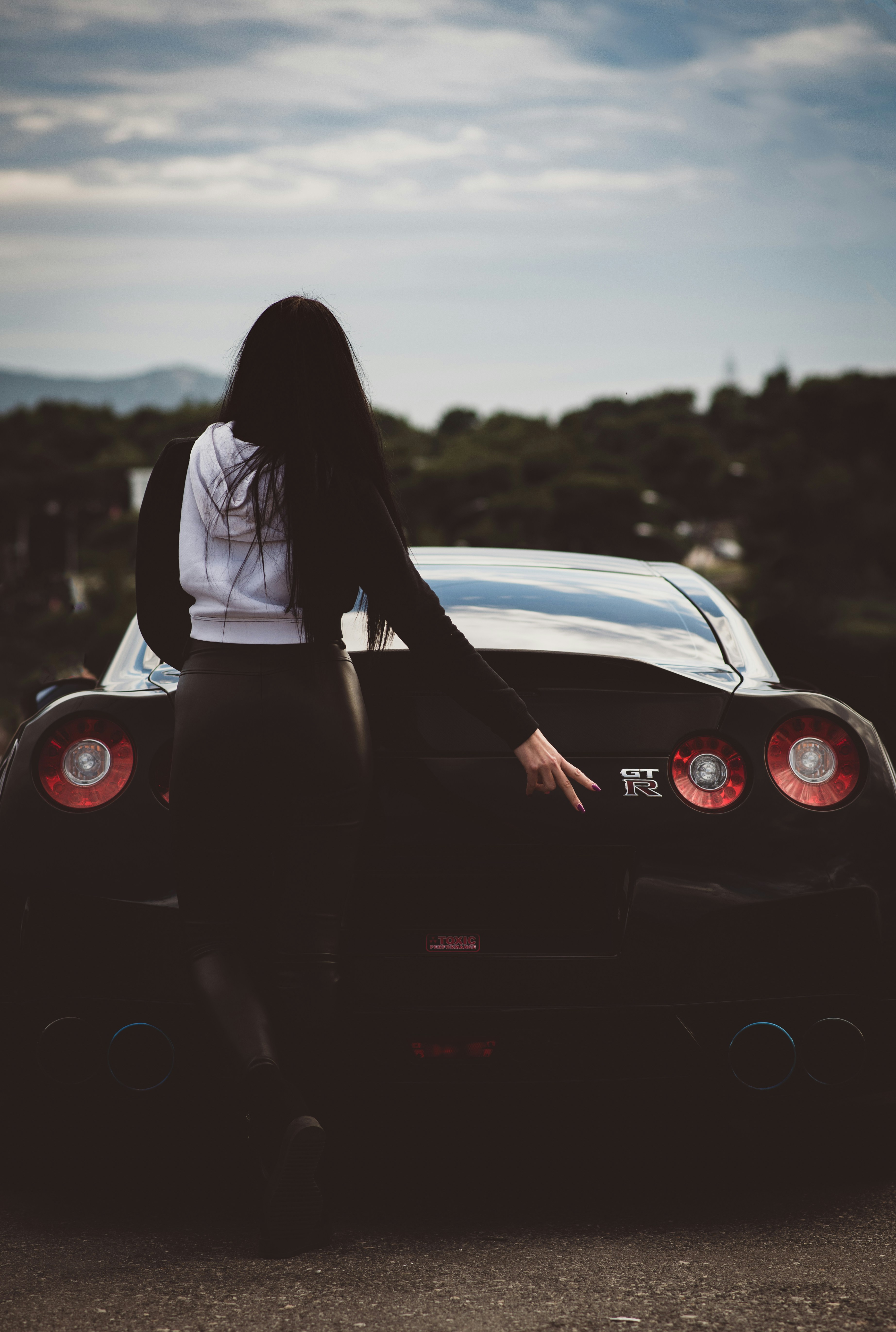 woman in black dress sitting on red car