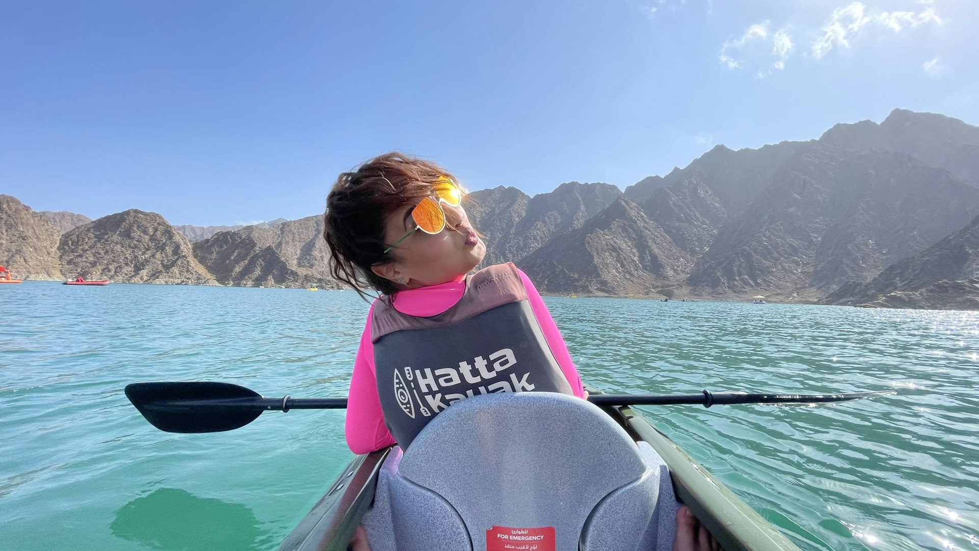 woman in pink and yellow life vest sitting on boat during daytime