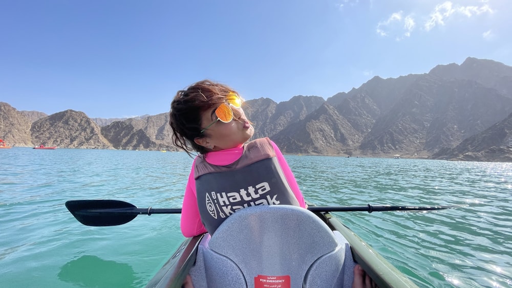 woman in pink and yellow life vest sitting on boat during daytime