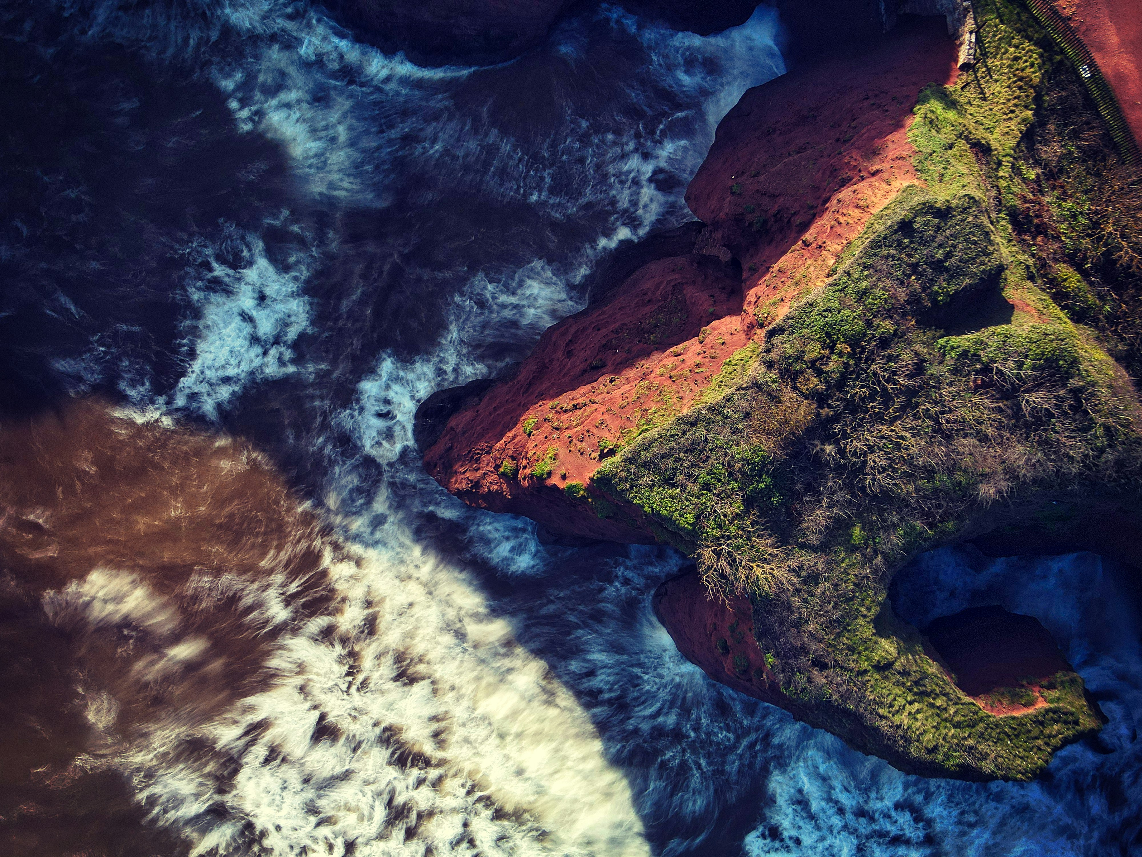 aerial view of ocean waves crashing on shore during daytime