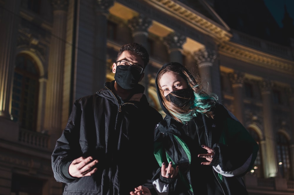 man in black jacket standing beside woman in green scarf