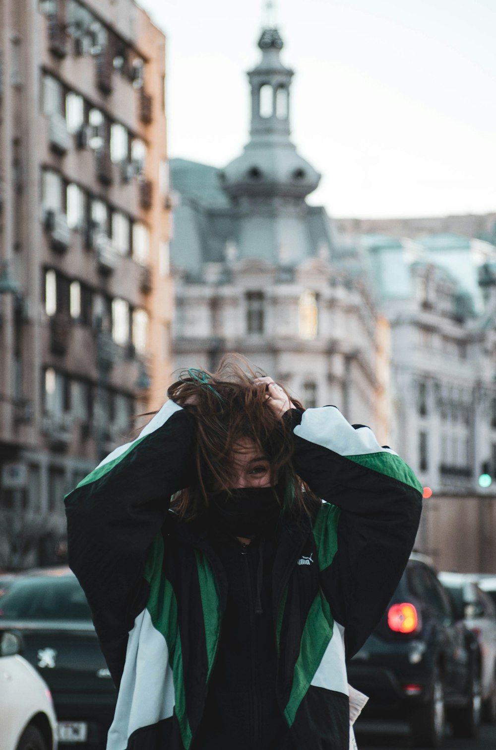 woman in green jacket covering her face with white scarf