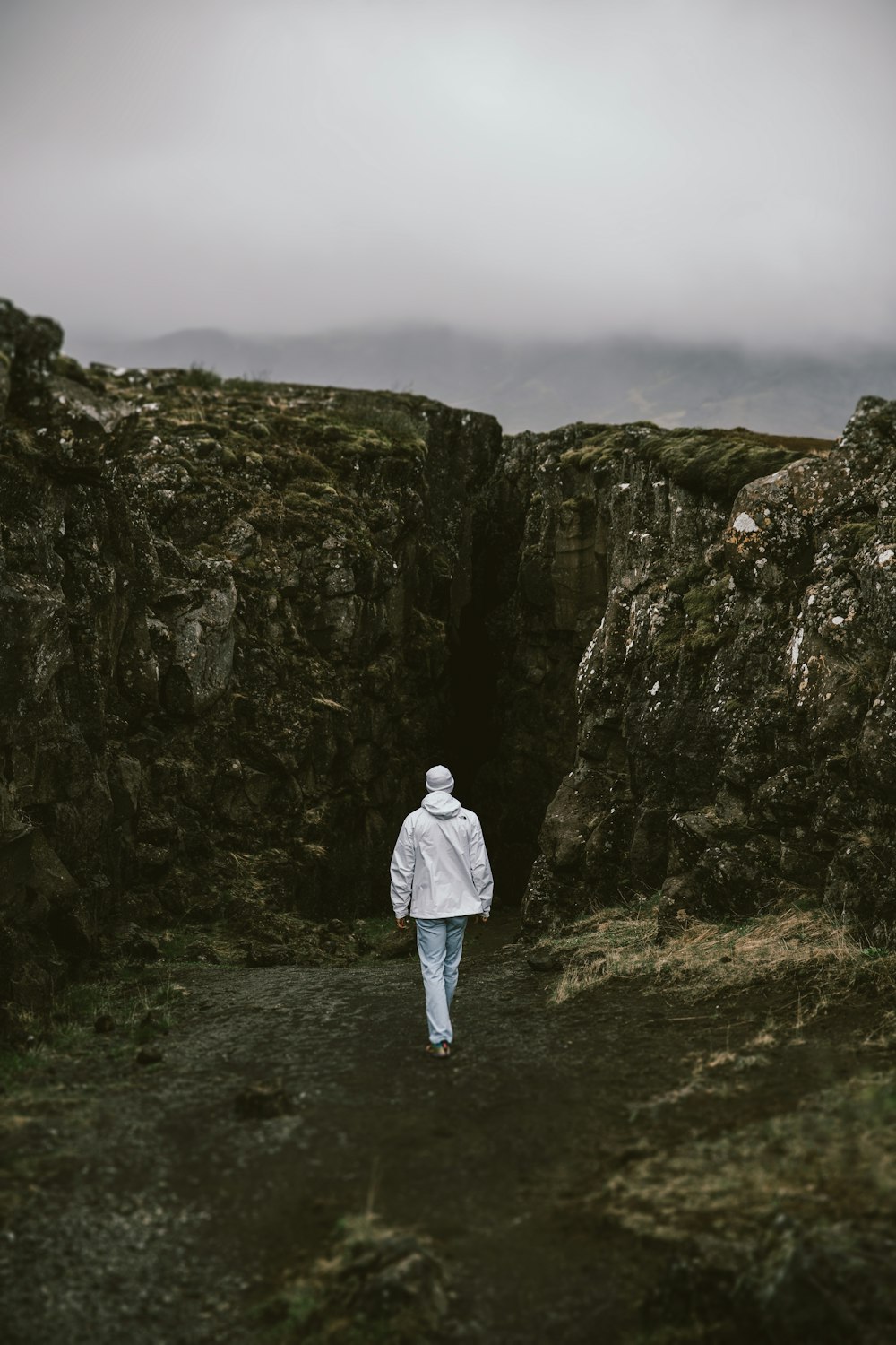 man in white jacket standing on gray rocky mountain during daytime