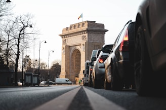 cars on road near brown concrete arch during daytime