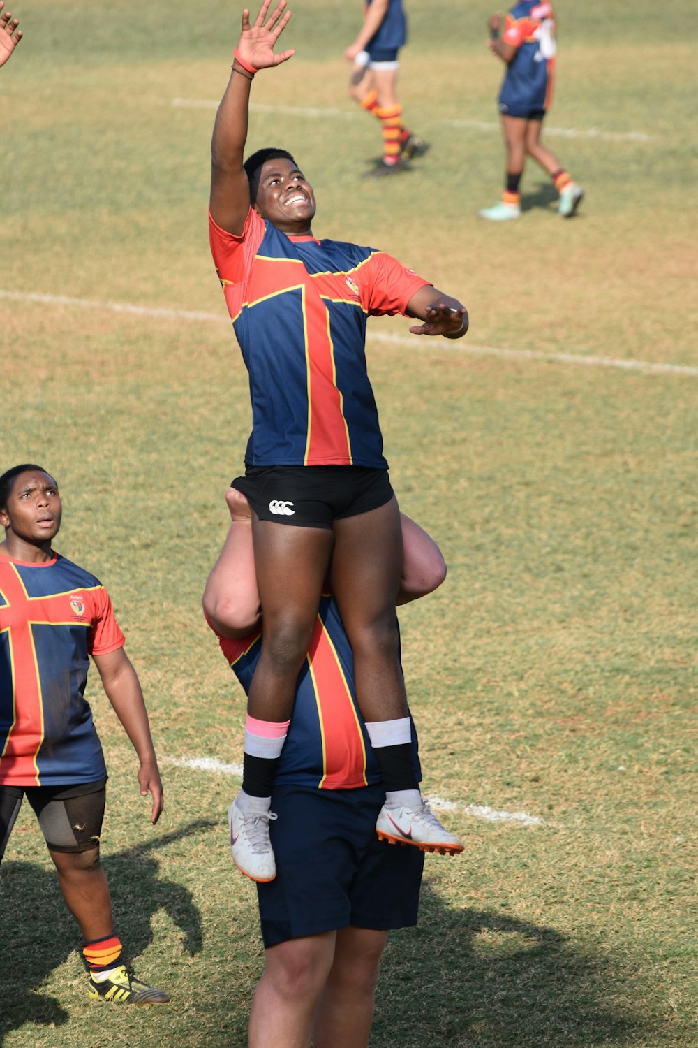 2 women in red and blue jersey shirt playing soccer during daytime