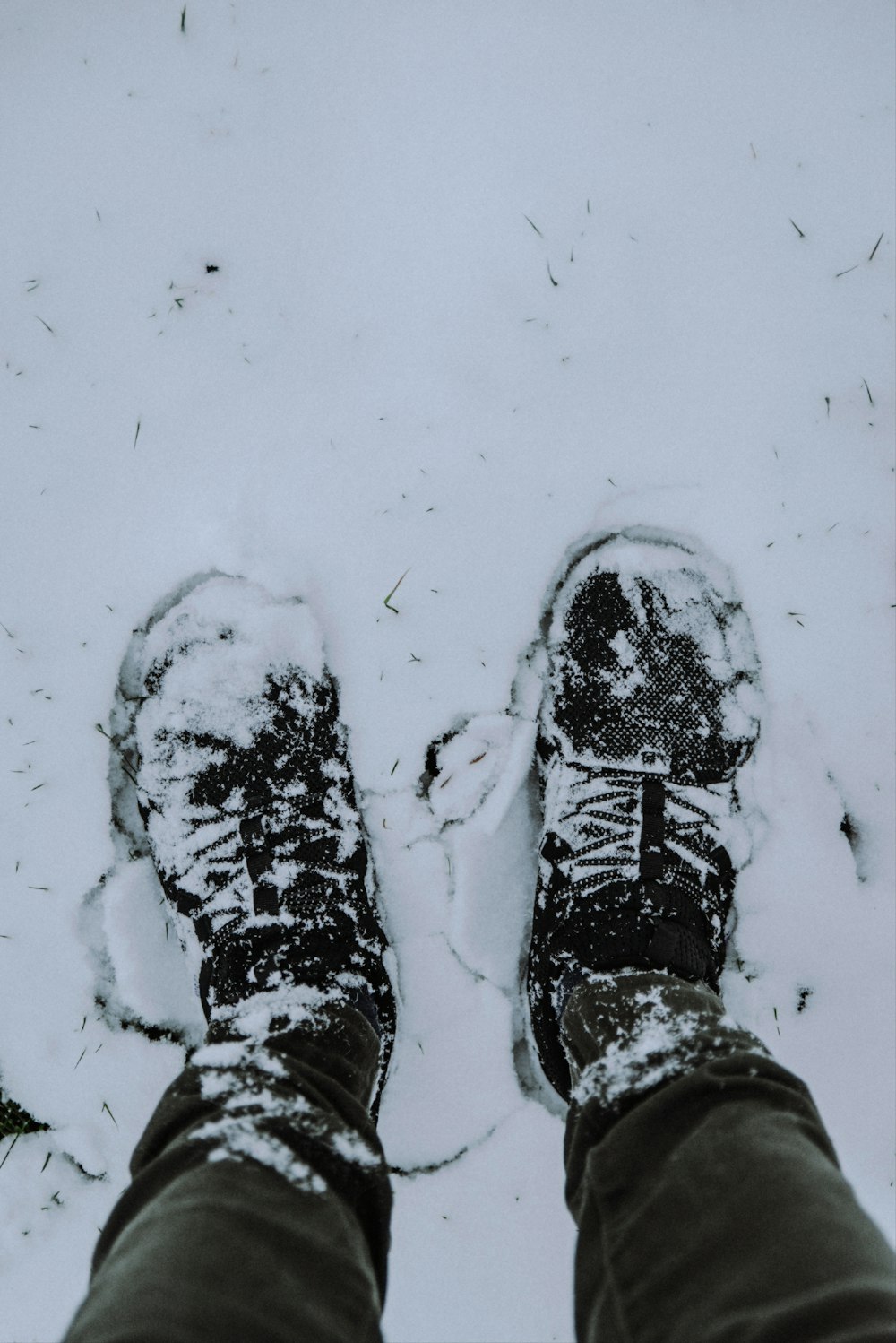 person in black and white hiking shoes standing on snow covered ground