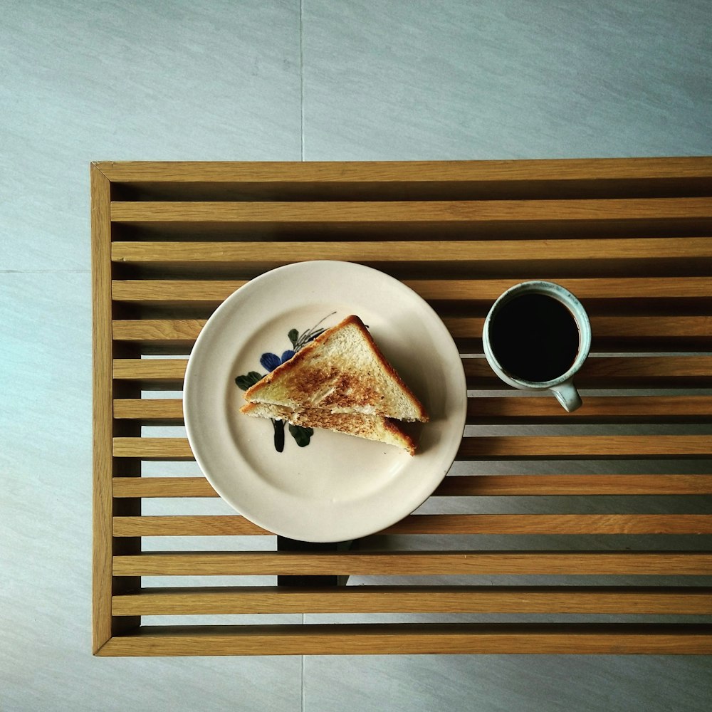 brown bread on white ceramic plate beside white ceramic mug on brown wooden table
