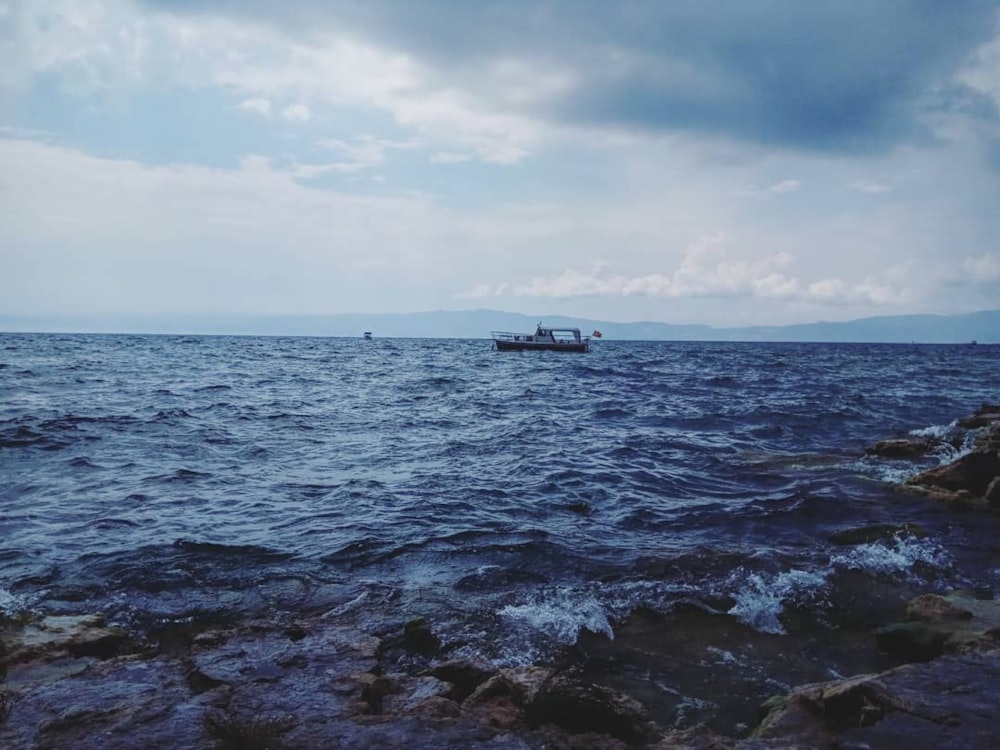 white boat on sea under white clouds during daytime