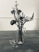 Close-up of freshly picked wildflowers in a small glass jar on a wooden table.